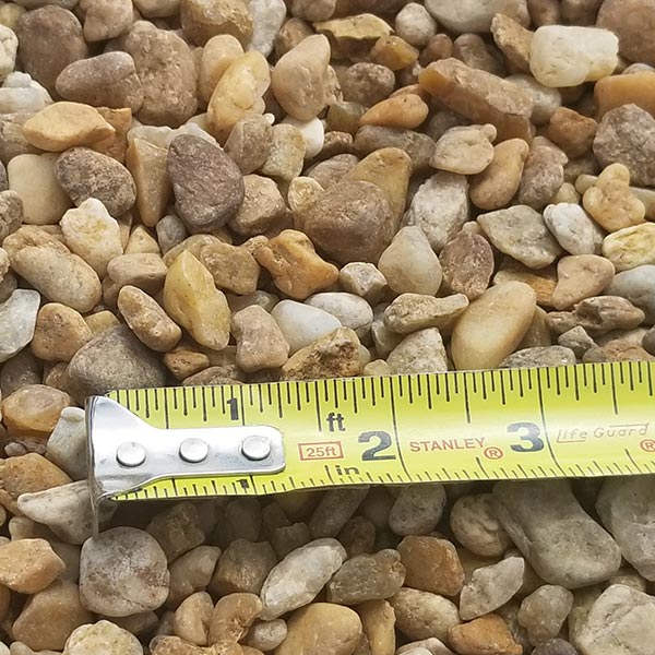 pile of pea gravel river rock with measuring tape