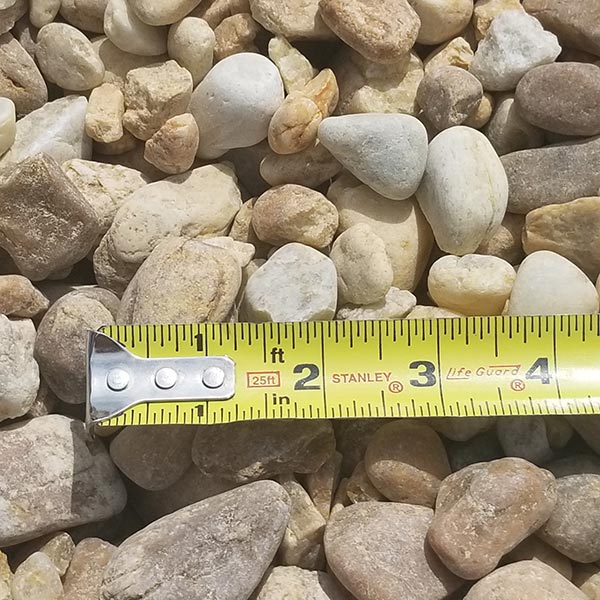 pile of medium river rock with measuring tape